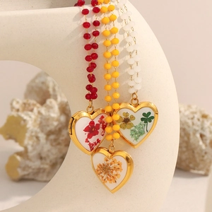 Detailed view of heart-shaped dried flower necklaces hanging on a ceramic vase