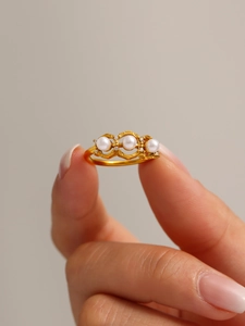 Close-up of three pearls set on a gold-plated stainless steel ring worn on a finger