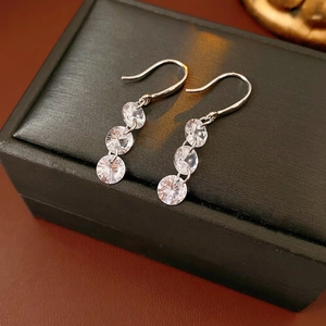 Minimalist silver drop earrings with three sparkling zircons on a luxury black leather box