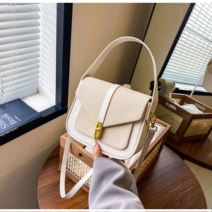 Detail of the woven fabric texture and gold twist lock on this beige saddle bag