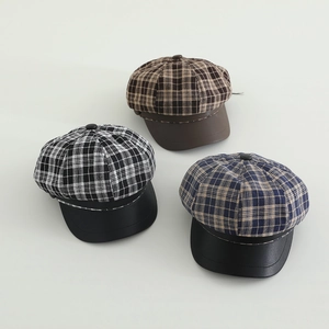 Detailed overhead view of girls plaid newsboy caps in brown, black and navy patterns