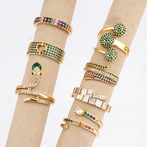 Collection of gold snake rings and floral gemstone jewelry on beige velvet stands
