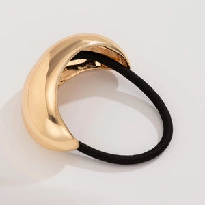 Detailed close-up of a polished gold metallic geometric buckle with a black elastic hair tie