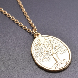 Detailed close-up of golden oval pendant featuring a Tree of Life design on O-chain necklace