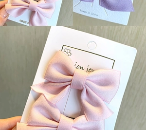 Detailed view of candy-colored satin bow hair clips on white retail display cards