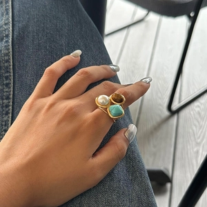 Détail de bague rétro avec œil de tigre, perle et turquoise sur métal doré