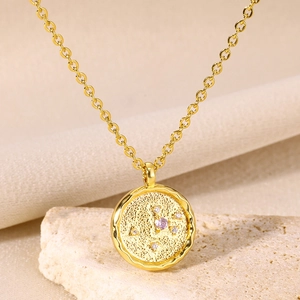 Macro detail of 18K gold zodiac pendant with purple zircon on stone and silk background