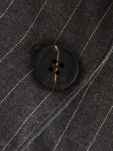 Gros plan sur le tissu à fines rayures gris foncé et le bouton à texture marbrée