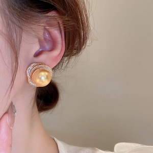 Gros plan détaillé d'une boucle d'oreille en perle dorée avec un cadre en cristal scintillant