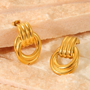 Polished 18k gold twisted geometric hoop earrings on a natural stone display