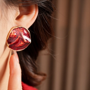 Detailed close-up of a red marble resin earring with elegant gold metallic edging