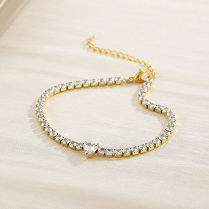 Detailed view of a gold-plated tennis bracelet with round zircons and a central heart gem
