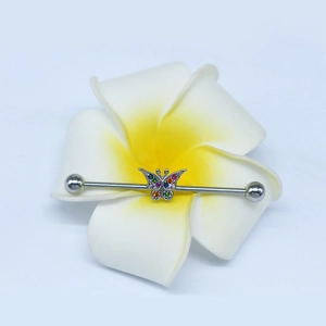 Macro detail of industrial barbell earring featuring a rainbow crystal butterfly on a flower