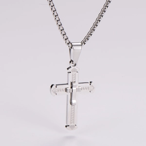 Detail of silver double-layered cross necklace with classic Greek Key pattern
