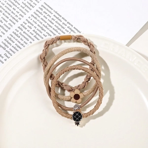 Close-up of four high-elastic hair ties with flower and crown charms in coffee tones