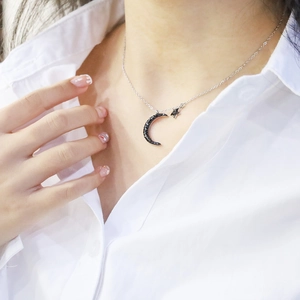 Star and black moon pendant necklace in silver stainless steel on a female model neck