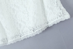 Gros plan sur la dentelle florale et les bords festonnés d'une robe courte blanche