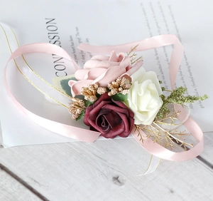Detail of pink and white faux rose wrist corsage with golden berries and satin ribbon