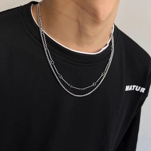 Detail of silver double-layer necklace with Cuban link and small rings on male model