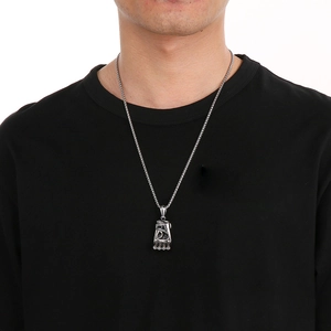 Détail d'un pendentif gant de boxe argenté porté par un mannequin en t-shirt noir