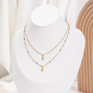 Detail of double-layer gold feather pendant necklace with pink and blue seed beads