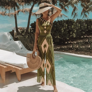 Detail of one-shoulder jumpsuit with green geometric patterns and wide-leg trousers