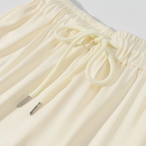 Dettaglio degli shorts in maglia crema con elastico in vita e coulisse con punte in metallo