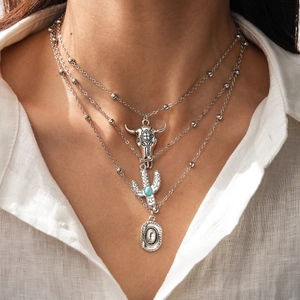 Detail of western style layered silver necklace with bull skull and cactus turquoise pendant