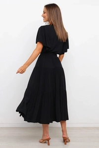 Detalle de un vestido largo negro con falda de capas y mangas con volantes desde atrás