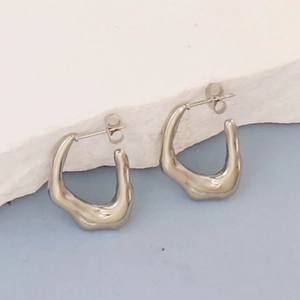 Macro detail of irregular silver geometric earrings with fluid lava textured design
