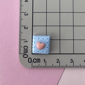 Macro shot of 1.5cm blue resin heart cookie charm with ruler for size reference