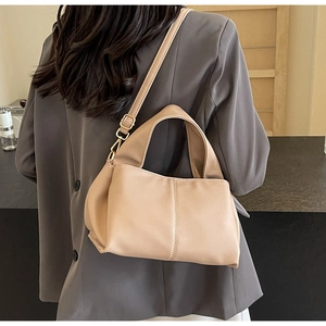 Detail of khaki leather handbag with gold buckle shown worn with a stylish blazer