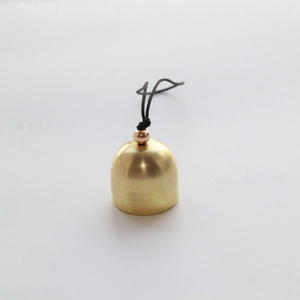 Macro view of a 2cm golden brass bell with smooth metallic finish and black hanging cord