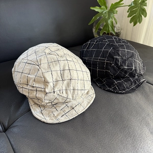 Detailed texture of plaid linen newsboy caps in black and beige on leather background