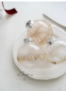 Detail of beaded champagne Christmas ornaments with shell accents in a white ceramic dish