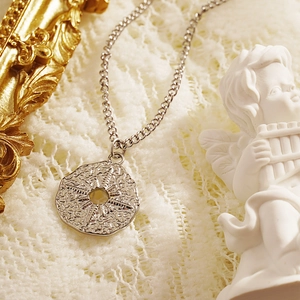 Vintage silver starburst pendant necklace featuring a hammered texture on a lace background