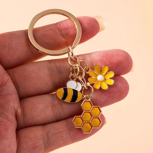 Golden keychain with bee honeycomb and sunflower charms featuring enamel drip oil craft