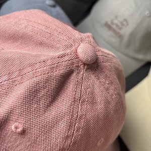 Detailed macro shot of pink canvas baseball cap showing fine stitching and fabric texture