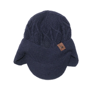 Détail de la maille et de l'écusson en cuir marron sur un bonnet d'hiver bleu marine