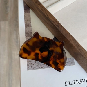 Macro view of cat-shaped tortoiseshell hair claw clip with amber pattern and black cat tail