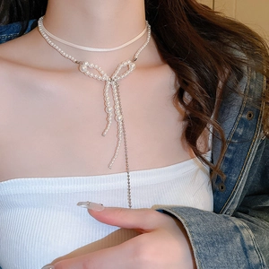 Detail of layered pearl bow necklace with long tassels on a model for an elegant look