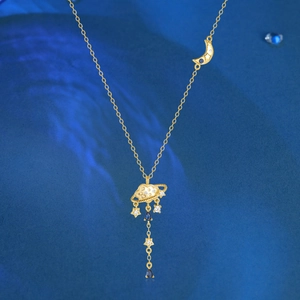 Close-up of gold planet and cloud pendant with blue gemstones and star tassels