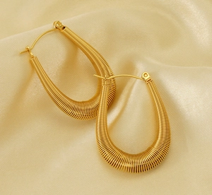 Detailed macro view of gold U-shaped lever back earrings with woven texture on silk