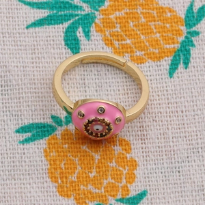 Detail of gold evil eye ring with pink enamel and sparkling white zircon stones