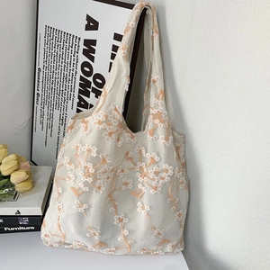 Detailed close-up of daisy embroidery on white mesh tote bag with a soft aesthetic