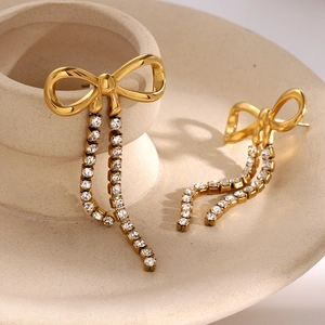 Close-up of 18k gold-plated bow earrings with shimmering double rhinestone tassels
