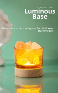 Close-up of a warm glowing amber glass diffuser with orange salt stones on a wooden base
