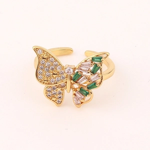 Detail of gold butterfly ring featuring green emerald-cut stones and white zircon crystals