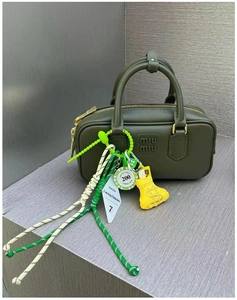 Detail of olive green leather handbag with decorative colorful braided rope pendants