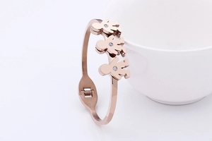 Detail of rose gold open bangle featuring hollow human-shaped pendants with micro-pave stones